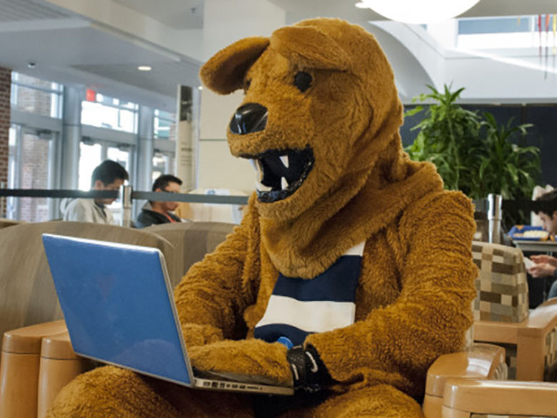 Nittany Lion using a laptop in the Library