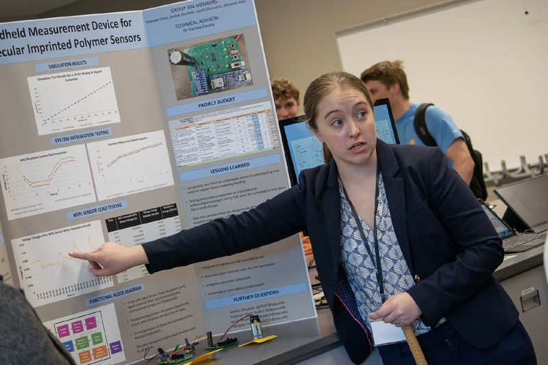A student points to her poster during the Capstone Design Conference