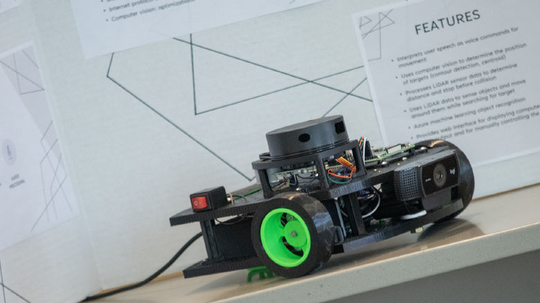 Photo of a voice-controlled robot sitting in front of a research poster