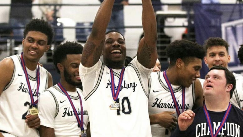 Clinton Asalu, surrounded by fellow members of the men's basketball team at Penn State Harrisburg, holds up a trophy in celebration