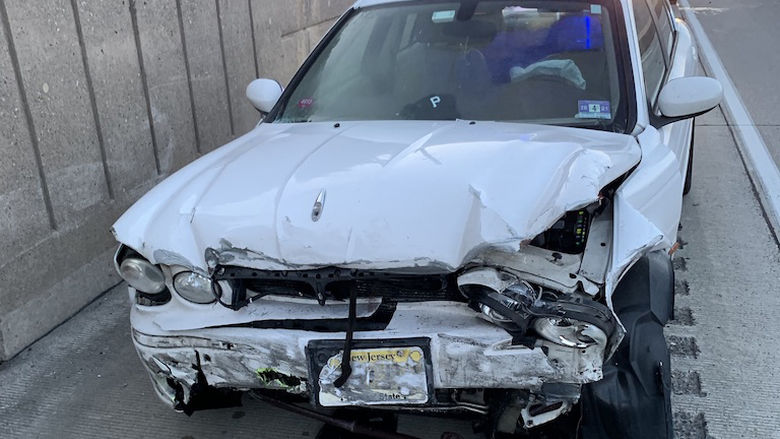 A white car, totaled, by the side of a highway