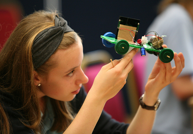 female student examines solar-powered model car