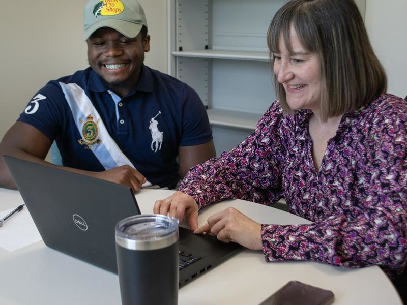A faculty member and a student look at a laptop