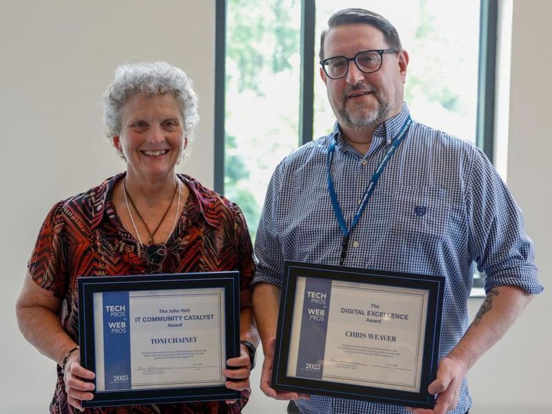 Toni Chainey and Chris Weaver pose holding framed awards