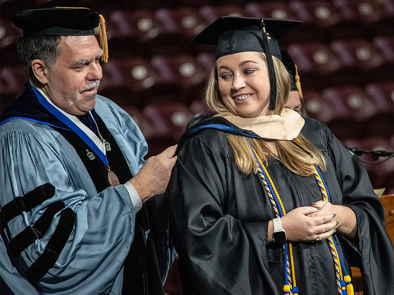 a Ph.D. recipient receives her doctoral hood during Commencement