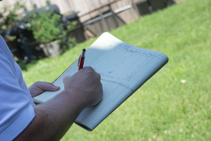 Closeup of someone outdoors, writing in a notebook