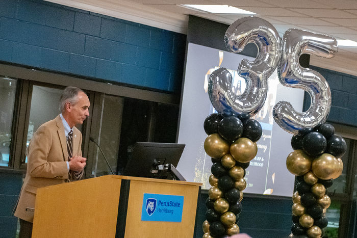 Penn State Harrisburg Chancellor John M. Mason Jr. speaks during the anniversary celebration for the Multicultural Academic Excellence Program. Large balloons shaped like the number 35 are in the background.