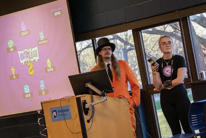 Two students stand next to a projector screen as they run games during a fundraiser 