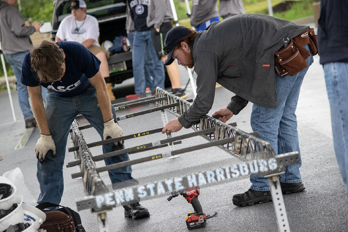 Two students work on a steel bridge during the ASCE competition