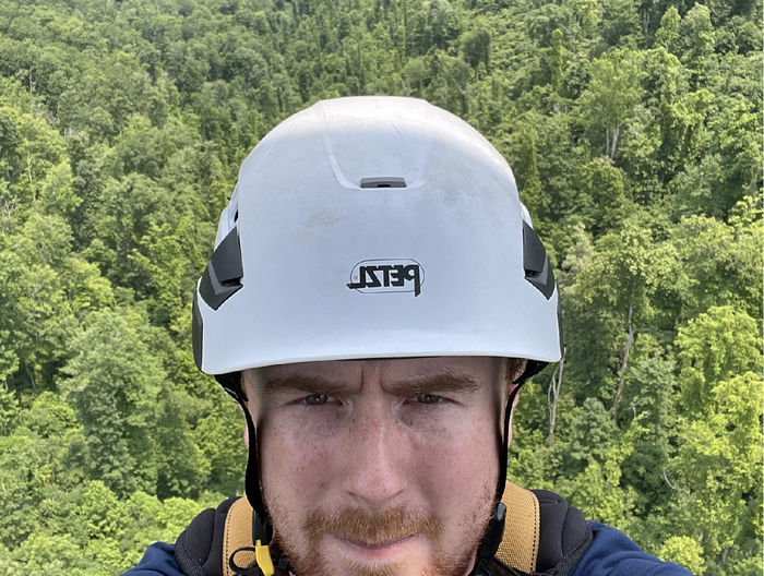 Selfie photo of Tyler Shearin with trees in background, taken from a cell phone tower
