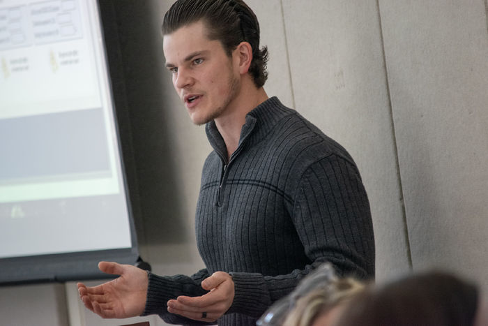 A man speaks in front of a large screen