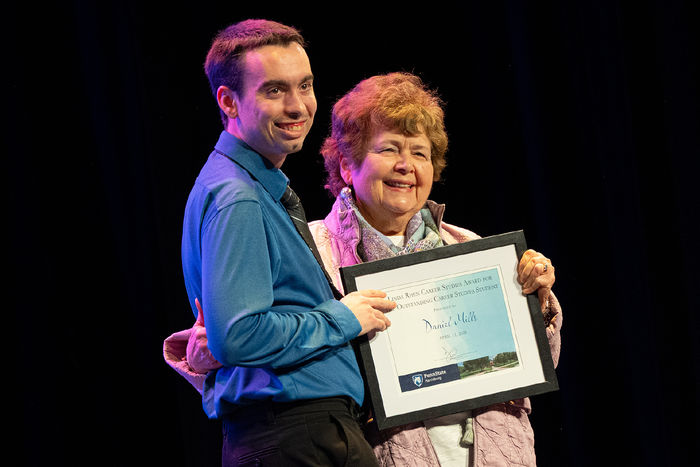 Daniel Mills and Linda Rhen pose holding a framed award certificate 