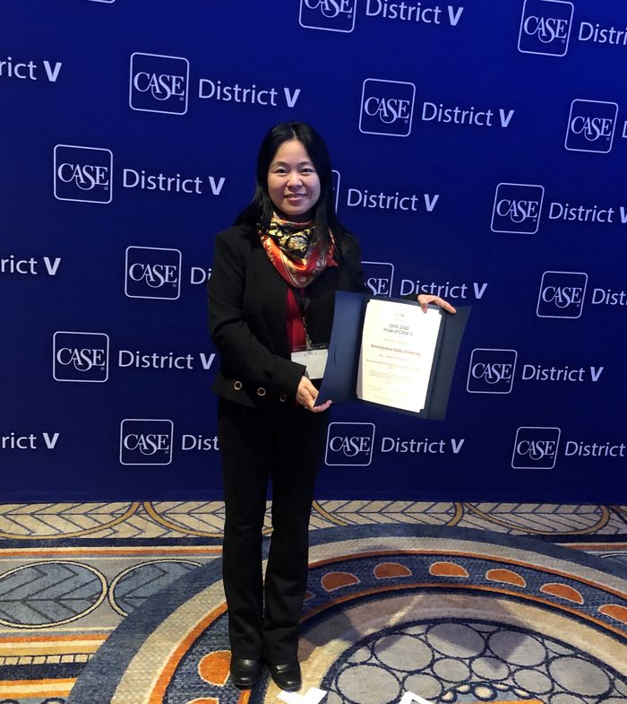 A woman holds an award in front of a CASE District V background