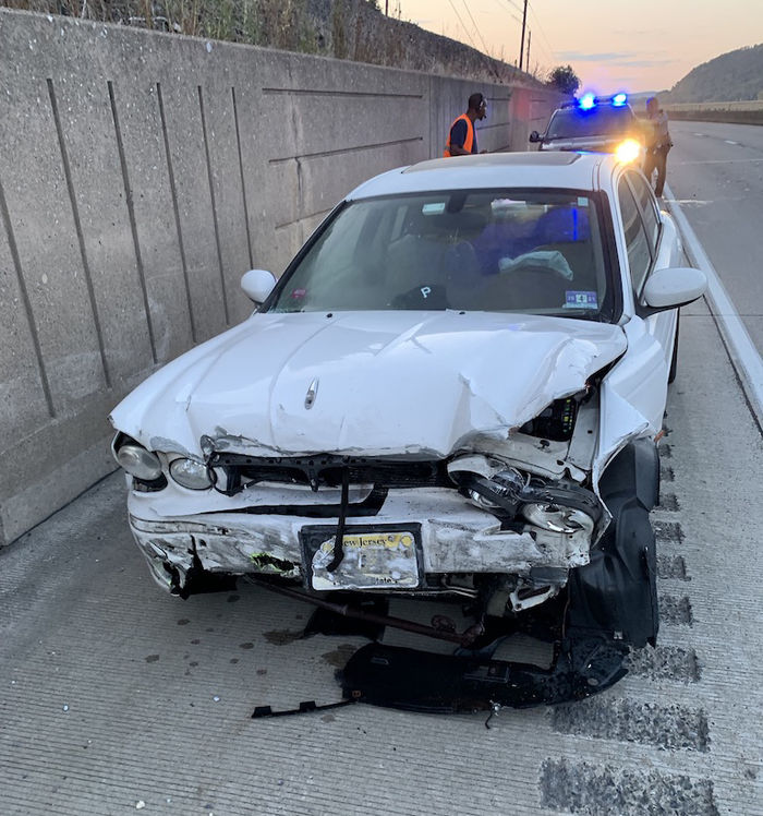 A white car, totaled, by the side of a highway