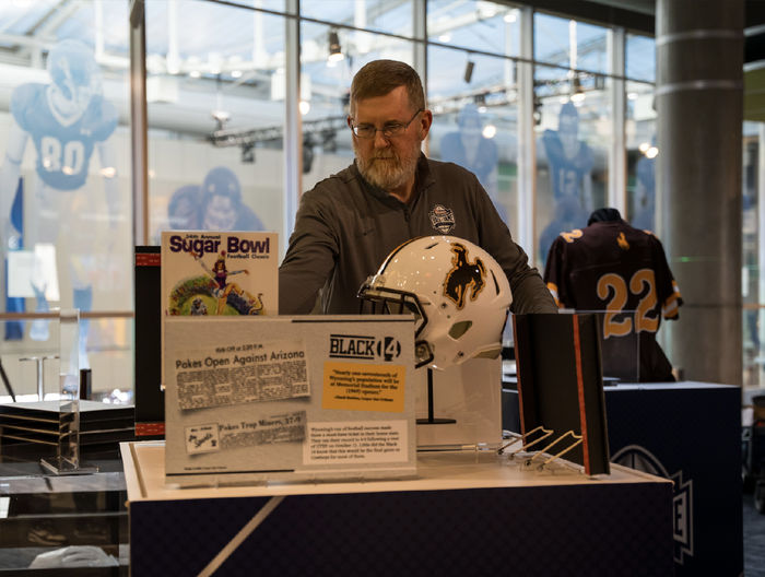 Denis Crawford adjusts an exhibit at the College Football Hall of Fame