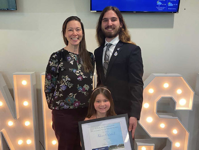 Fabian Vantassell poses with a professor and his little sister, who holds an award he received