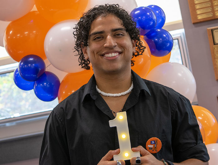 First-gen student Juan Serrano holds a light shaped like a 1