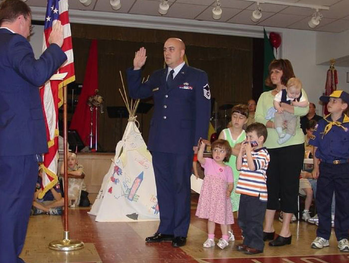 Gary Barb raises his right hand during his final reenlistment ceremony, surrounded by family