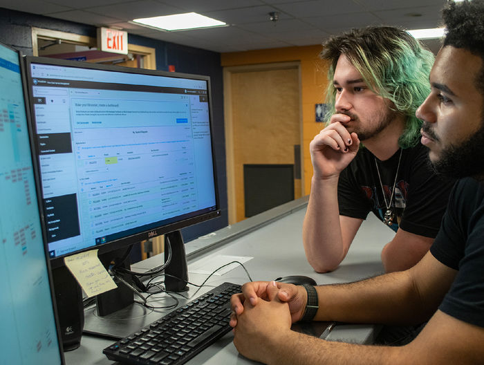 Two students look at a computer screen while working on the ITS Service Desk.