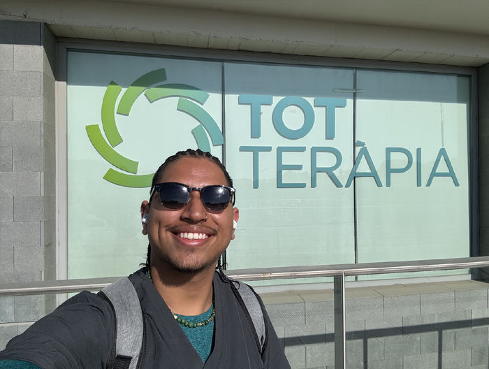 Juan Serrano in a selfie photo in front of a sign for Tot Teràpia