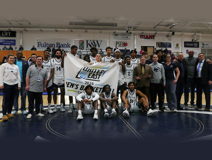 Penn State Harrisburg Men's Basketball team with a banner that says United East 2024 Men's Basketball Champions