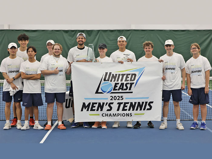 A group of men holding the United East 2025 Men's Tennis Champions banner