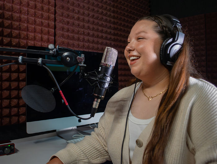 A student speaks into a microphone in a podcast studio
