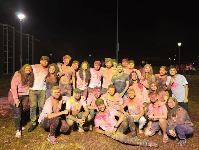 Patel and large group of people covered in colored powder for Holi
