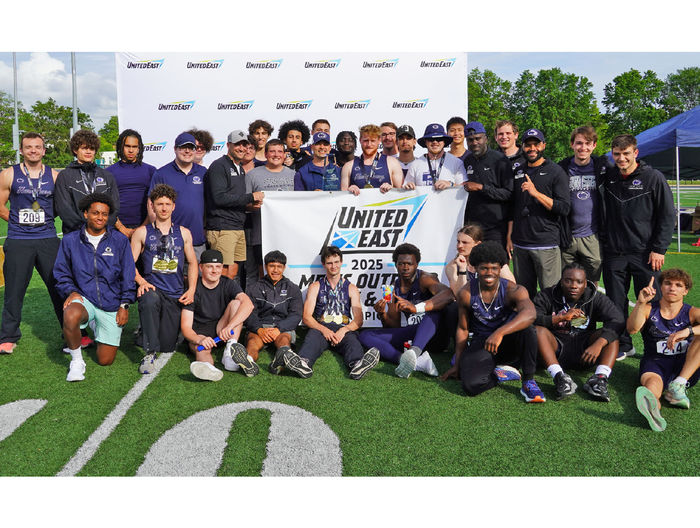 Track and field athletes gather around a championship banner