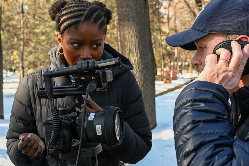 A student points a camera at a subject talking on a cell phone