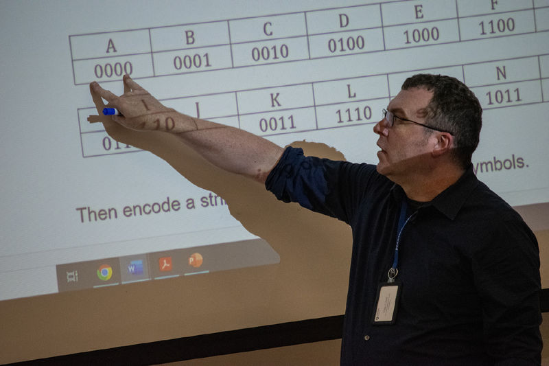 Craig Culbert, assistant teaching professor of mathematical sciences at Penn State Harrisburg, points to information on a large screen.  