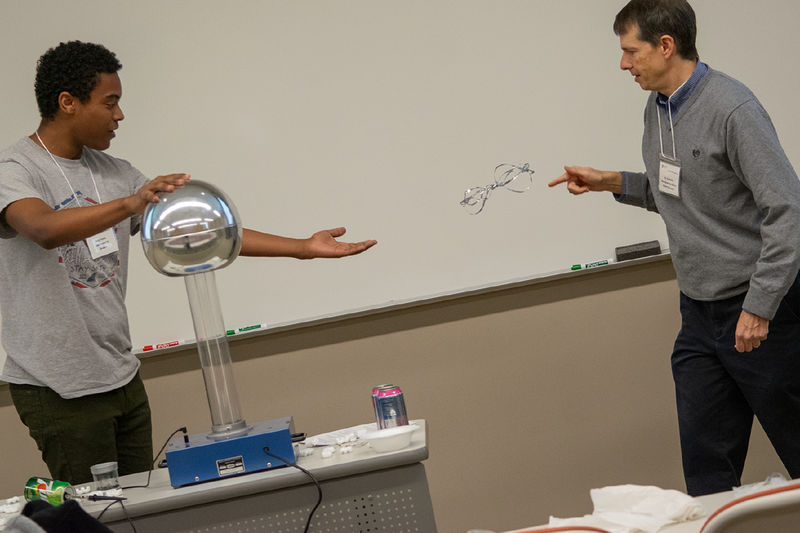 A student and professor do an experiment with an electrostatic generator