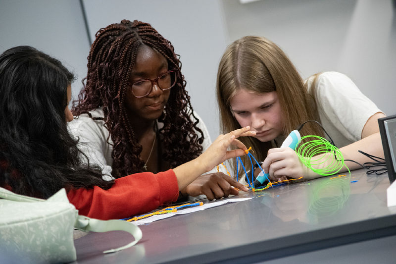 Students use a 3-D printing pen to craft a bridge