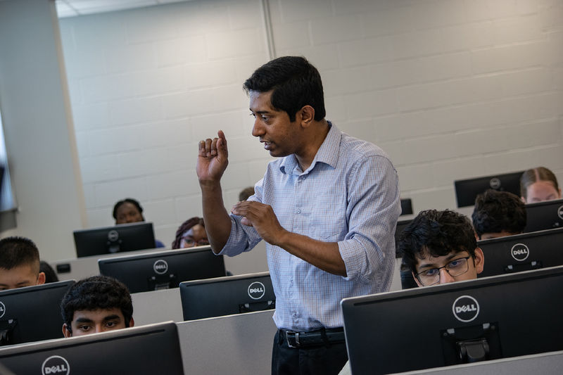 A professor instructs students sitting at computers