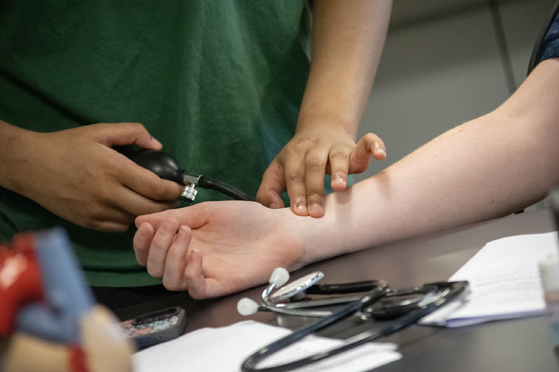Closeup of a student checking another's pulse while taking blood pressure readings