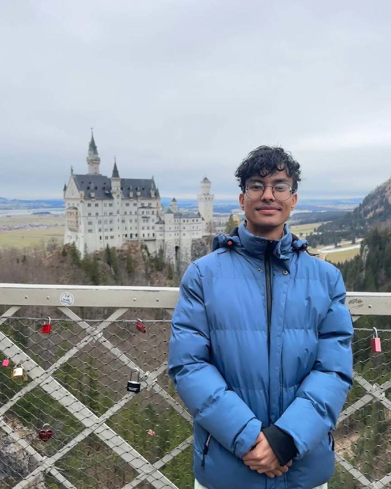 A student poses in front of a far-away castle