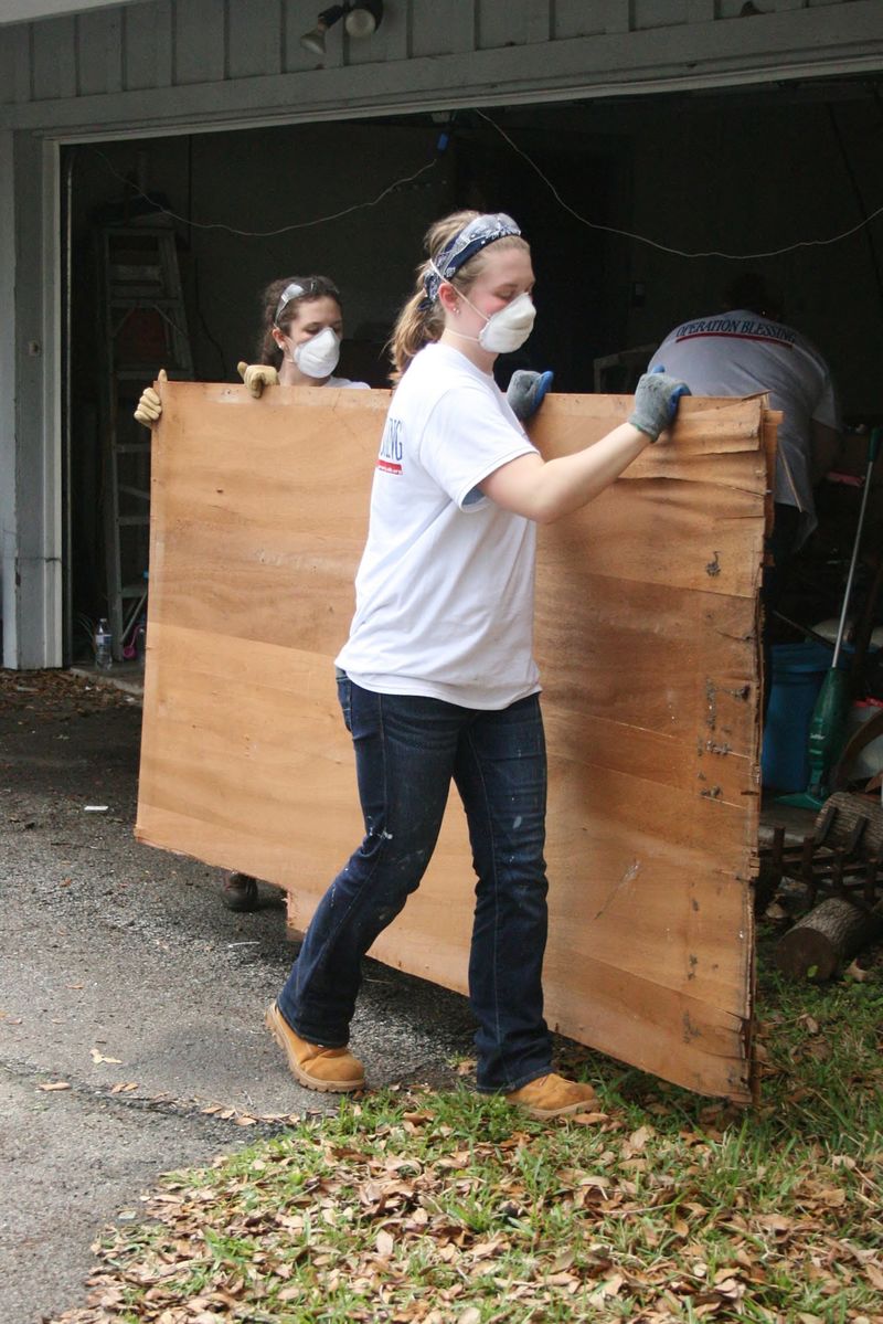 Two Penn State Behrend students remove a damaged section of wall from a home in Houston.