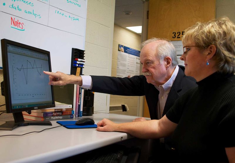 male pointing at graph on screen, woman looking on
