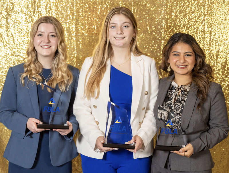 Three women hold FBLA trophies