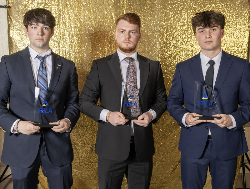 Three students hold FBLA trophies