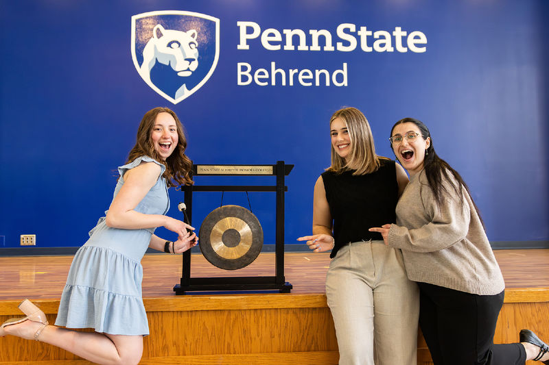 A group of Scholars stand in front of the gong at PSU Behrend