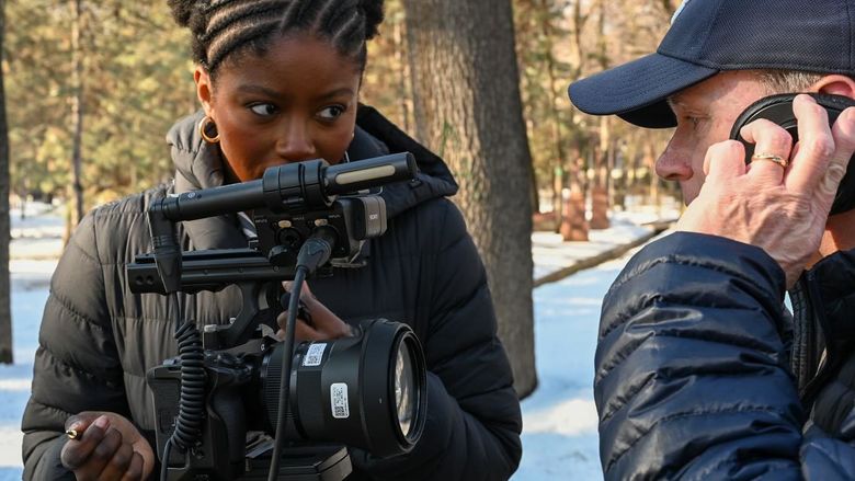 A student points a camera at a subject talking on a cell phone