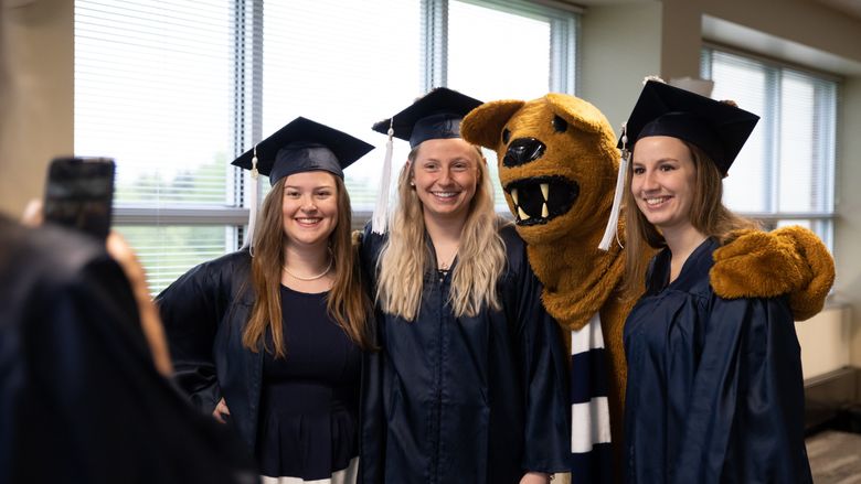 Three female graduates pose with Nittany Lion mascot