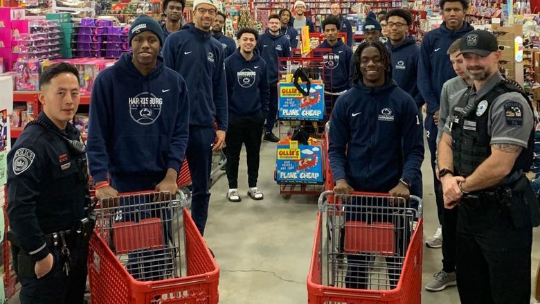 two police officers and several men's basketball players pose with carts in a store