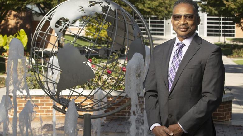 Professor Roderick Lee stands near globe fountain at Penn State Harrisburg