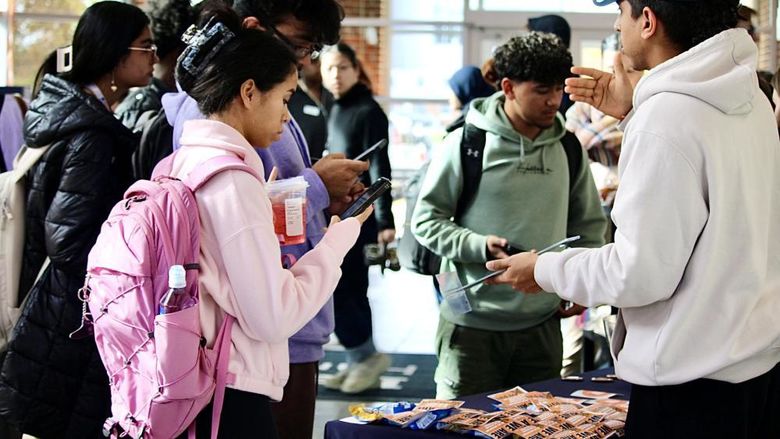 Students approach an information table during a first-gen student event in Olmsted Building atrium