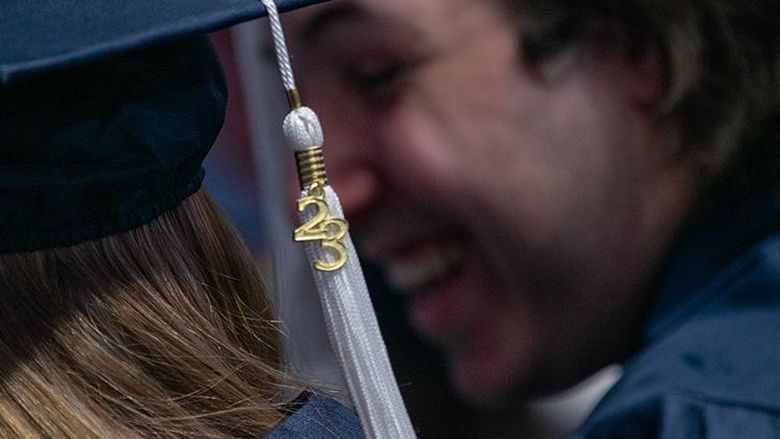 A class of 23 tassel dangles in front of smiling graduate faces
