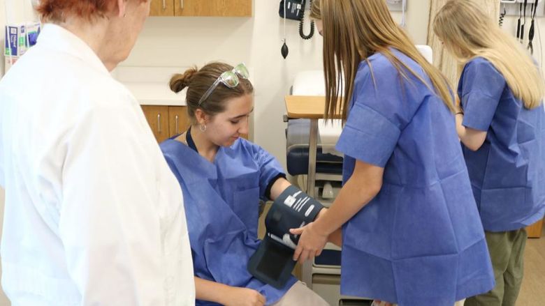 MedCamp 2024 participants checking vitals while Nursing professor observes.