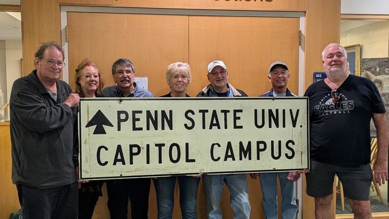 7 Penn State Harrisburg alums and family members pose with a sign that says Penn State Univ. Capitol Campus