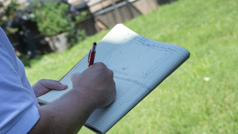 Closeup of someone outdoors, writing in a notebook